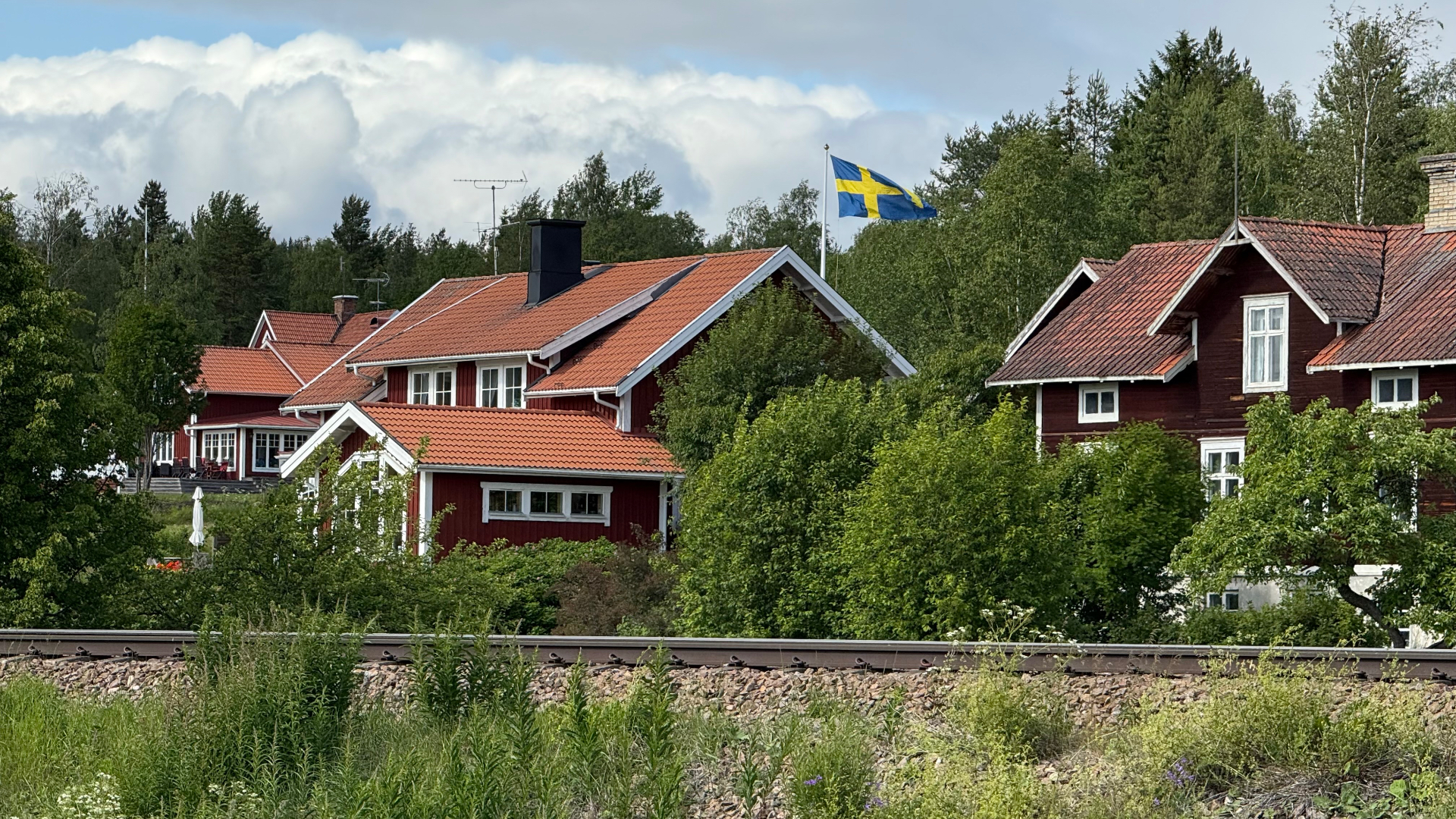 Falu-red houses and the Swedish flag. The villages runners pass between stages.